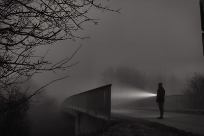 Man with flashlight standing on road at night