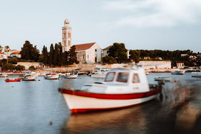 Sailboats moored in city by buildings against sky