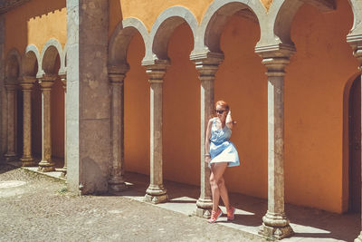 Young woman standing amidst columns of historical building