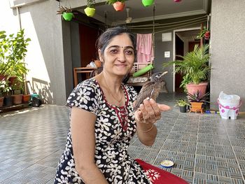 Portrait of smiling woman holding potted plant