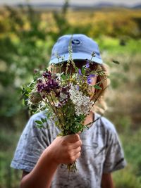 Boy holding bouquet on field