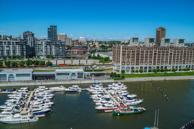 Sailboats moored on river by buildings in city against sky