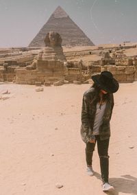 Full length of woman standing on sand against pyramid