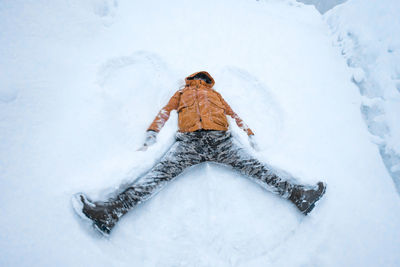 High angle view of man lying down on snow