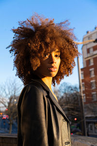 Young woman standing against sky