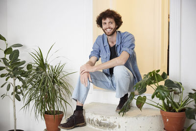 Full length portrait of smiling man sitting at entrance of art class