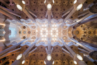 Low angle view of illuminated chandelier hanging on ceiling in building