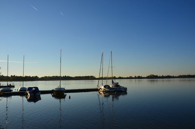 Boats sailing in lake against clear blue sky