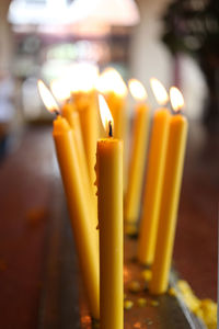 Close-up of lit candles on table in temple