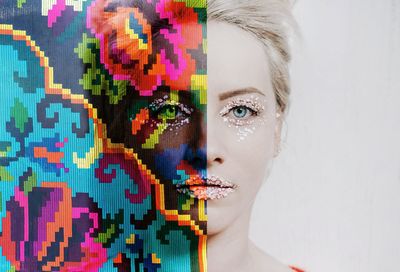 Digital composite image of woman with make-up and colorful pattern against wall