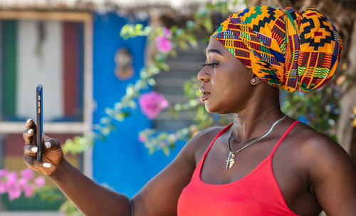 African woman taking selfie picture with colorful traditional african headdress