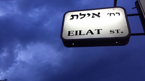 Low angle view of sign board against blue sky