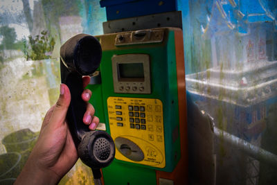 Cropped hand of person holding old pay phone