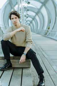 Portrait of young man sitting on footbridge