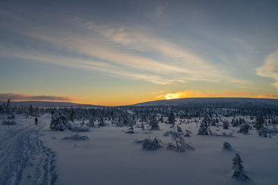 Scenic view of snow covered landscape against sky at sunset