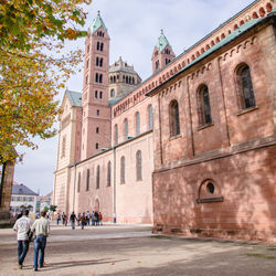 People walking by historic buildings against sky