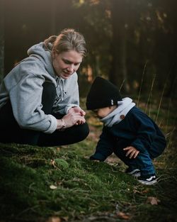 Mother looking at son crouching on field