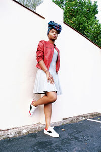 Portrait of young woman standing against wall