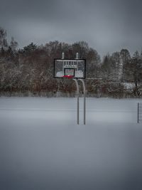 Basketball hoop on snowy field against sky