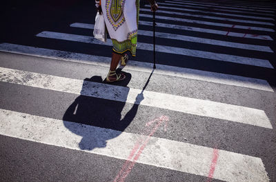 Single person walking across the street zebra while using a cane walking stick in new york city