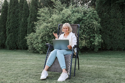 Woman using mobile phone while sitting on tree