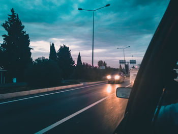 Cars on road against sky in city