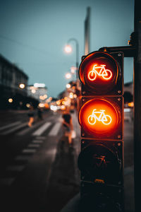 Illuminated road signal on city street at night