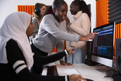 Girl pointing at desktop screen while talking to composer in studio