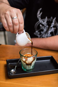 Midsection of man preparing food in glass on table