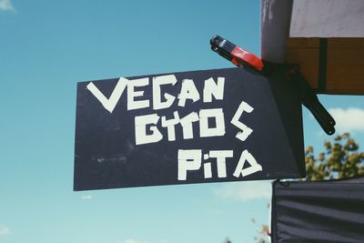 Low angle view of sign board against blue sky