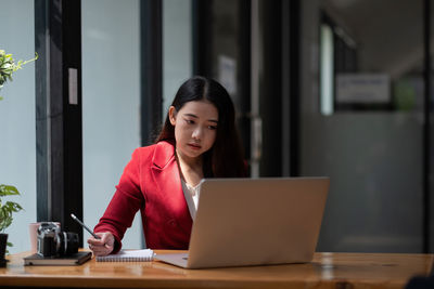 Woman using phone while sitting on table