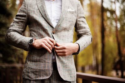 Midsection of well-dressed man standing in park