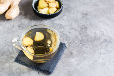 Fresh ginger tea in a cup and chopped ginger in a bowl on the table. natural vitamins.