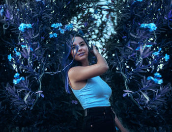 Portrait of young woman standing by tree