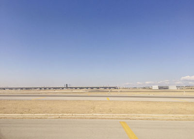 Airport runway against sky during sunny day