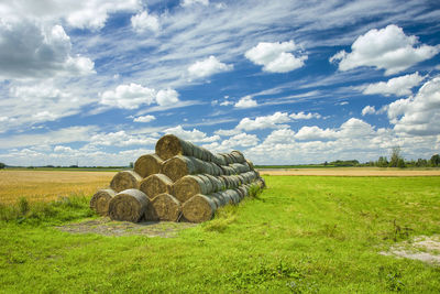 Stacked hay bales in the meadow and clouds in the sky, summer view
