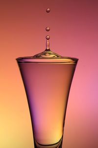 Close-up of beer glass against orange background