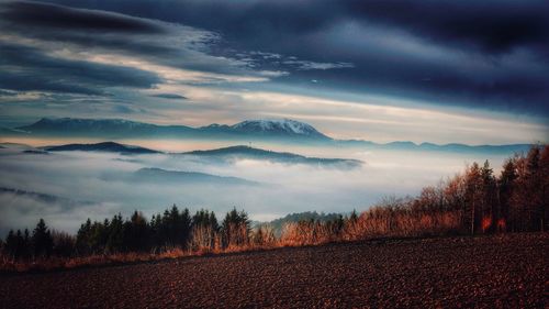 Scenic view of landscape and mountains against cloudy sky