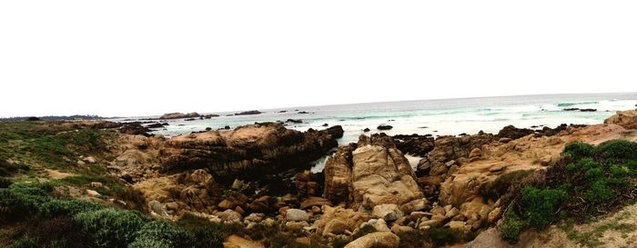 Scenic view of cliff by sea against clear sky