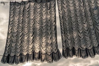 Full frame shot of curtains hanging on clothesline, silhouetted against cloudy sky