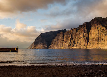 Scenic view of sea and mountains against cloudy sky