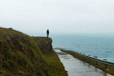 Man standing on shore by sea against sky