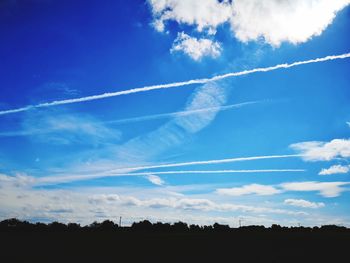 Low angle view of silhouette trees against blue sky