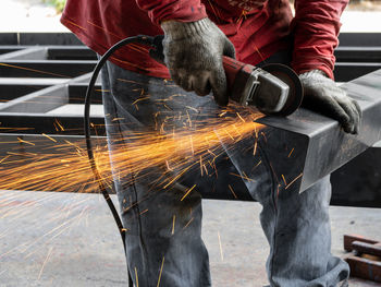 Midsection of man cutting metal