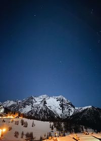 Snowcapped mountains against blue sky at night