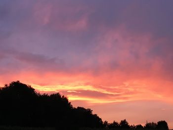 Low angle view of silhouette trees against dramatic sky