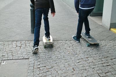 Low section of people skating on sidewalk