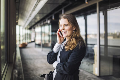 Smiling businesswoman talking on phone while standing at workplace