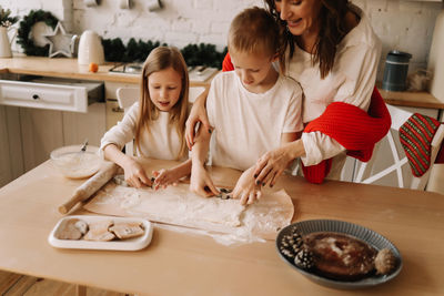 A happy family together carve festive cookies out of dough at christmas in the kitchen at home