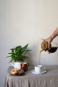 Cropped hand of person pouring coffee in cup on table